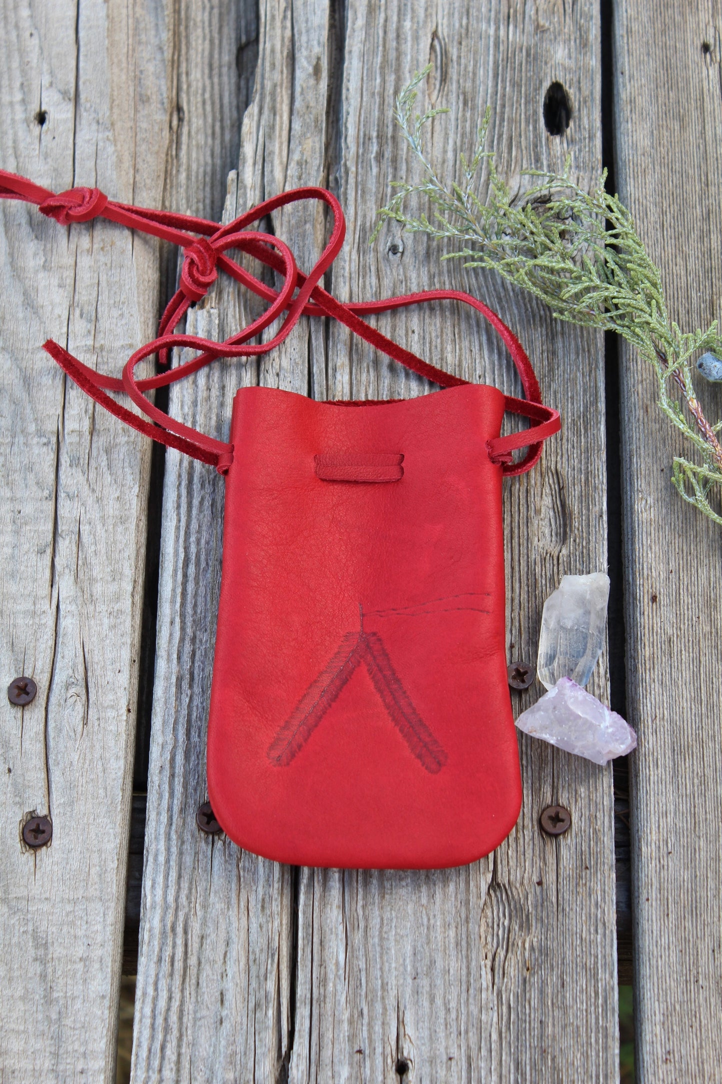Red leather medicine bag with burned feathers